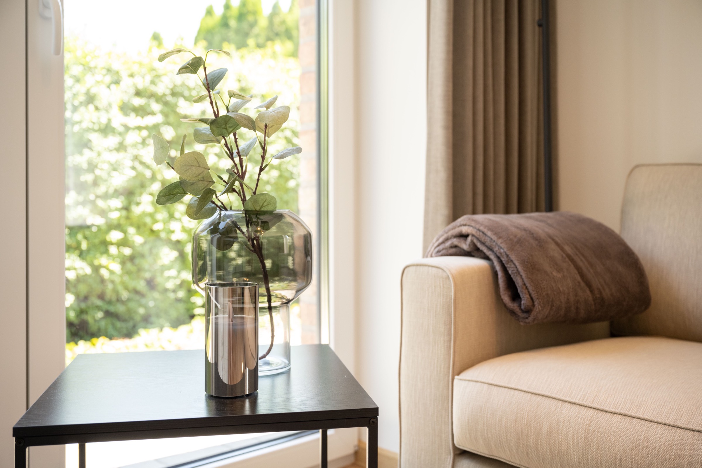 Detail in einem SUITES Apartment: Beistelltisch mit Vase vor bodentiefem Fenster