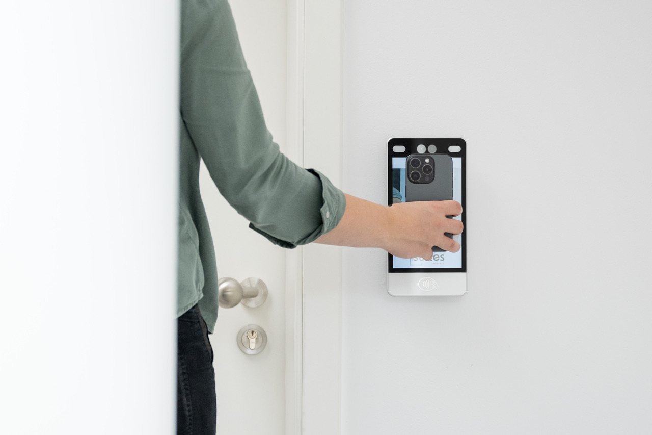 Gast hält das Smartphone an das digitale Türterminal eines SUITES Apartments
