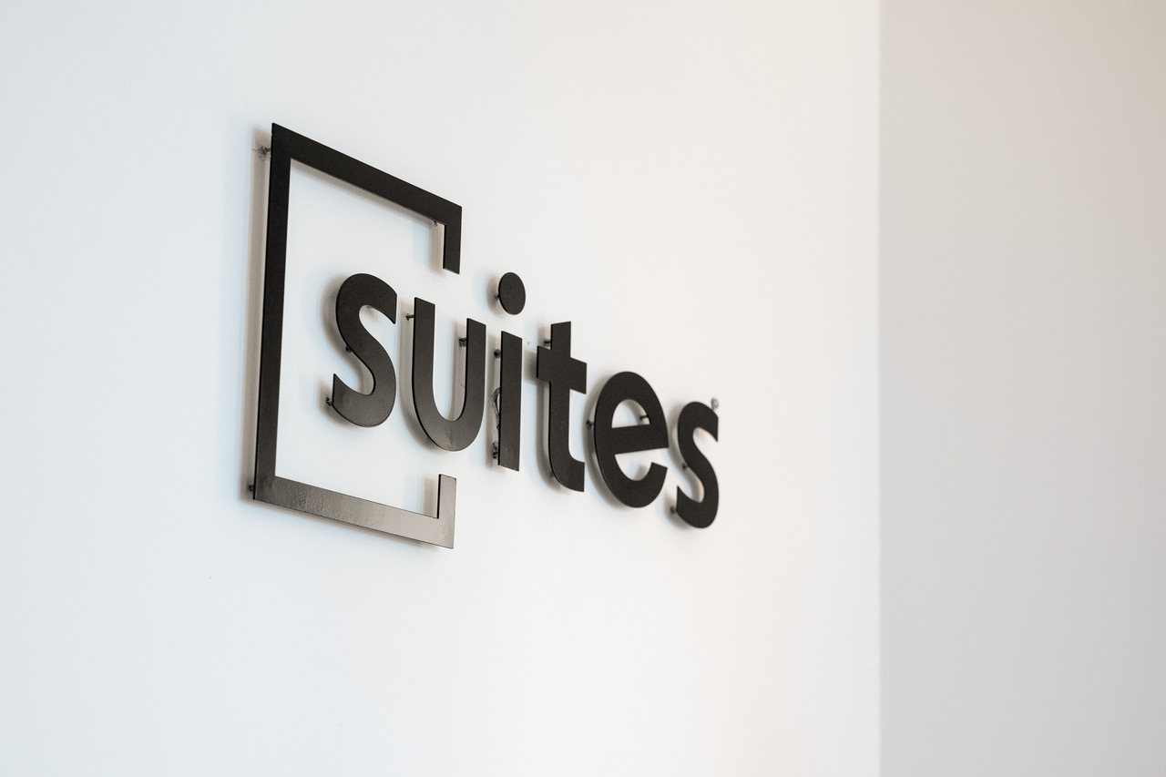 SUITES-Logo als Metallschriftzug an der Wand